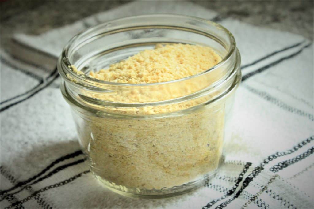 vegan cashew parmesan in a small bowl on a checkered white and black background. 