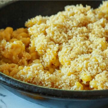 Vegan macaroni and cheese in a black skillet with panko crumbs.