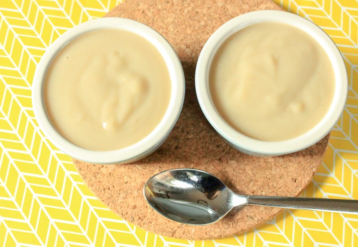 vegan vanilla pudding in two small white ramekins with a spoon and a yellow and white background. 