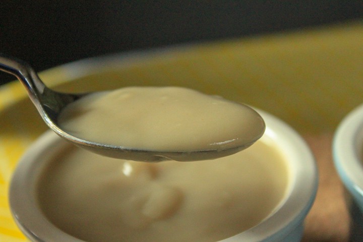 vegan vanilla pudding in a spoon over a small bowl of pudding. 