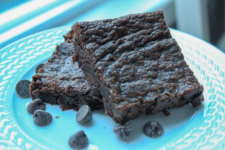 two brownies on a white plate with chocolate chips sprinkled. 