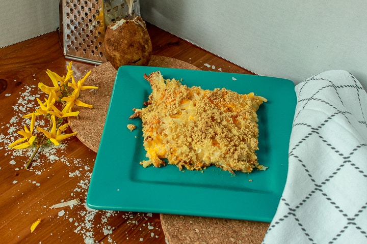 cheesy vegan hash brown casserole on a square teal plate. 