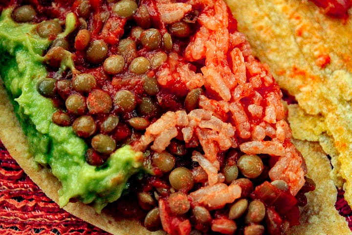 vegan taco with lentil taco meat made up into a corn tortilla with lentils, mexican rice and guacamole. 