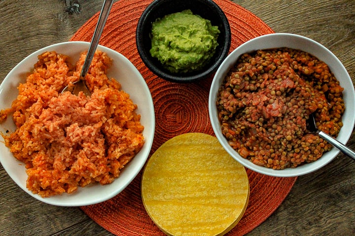 vegan lentil taco meat spread with a photo of multiple bowls one filled with mexican rice one with the lentil meat and one with guacamole then a stack of corn tortillas. 