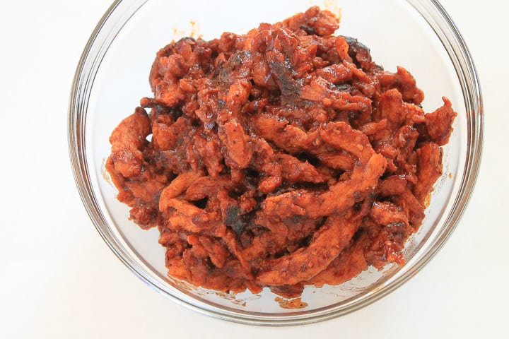 vegan pulled pork soy curls in a clear bowl on a white background. 