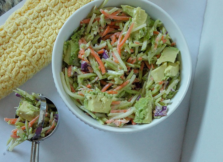 vegan brocolli slaw in a white bowl on a white background. 