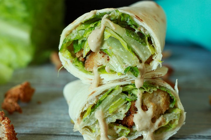 vegan Caesar salad wrap stacked close up shot with sauce dripping down the front. 