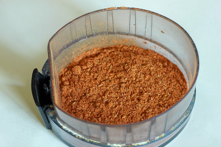 vegan pepperoni seasoning in the lid of a grinder on a white background. 