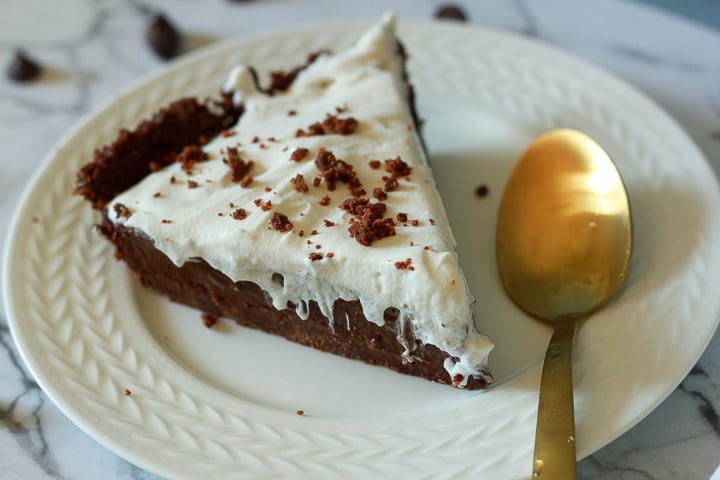 vegan chocolate cream pie slice on a white plate with a gold spoon. 