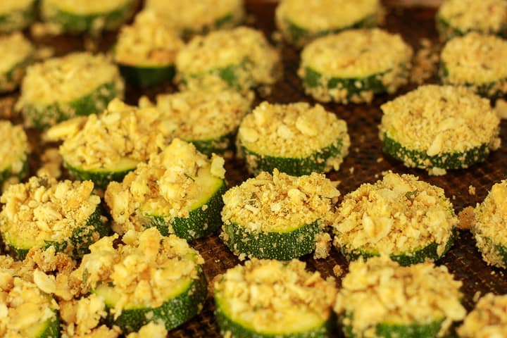 zucchini slices with cashew parmesan on a cookie sheet. 