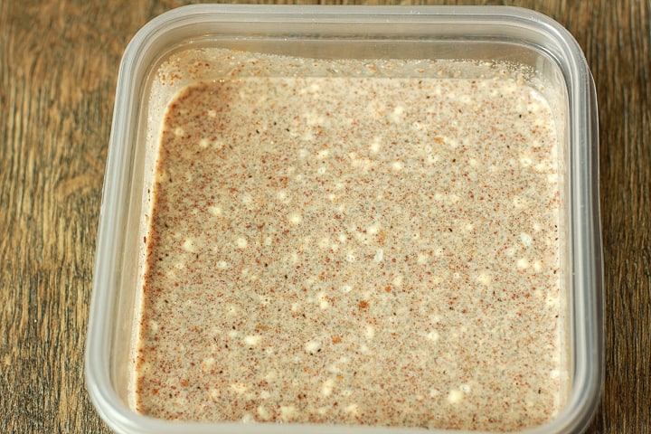 vegan french toast batter in a plastic container on a wood background. 