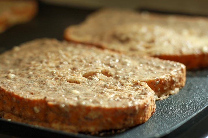 vegan french toast cooking on a black griddle. 