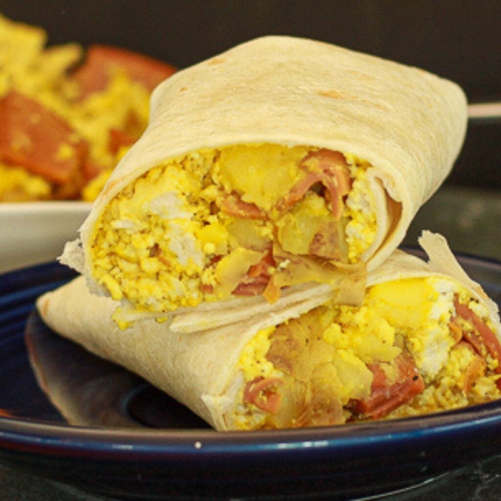 vegan breakfast burritos stacked on top of each other on a blue plate. 