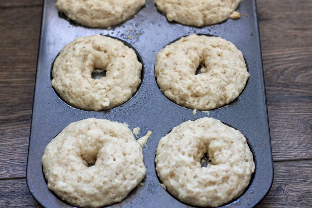 baked vegan donuts in a 6 donut donut pan on a wood background. 