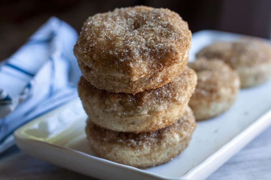 cinnamon and sugar vegan donuts stacked three high on a white plate. 