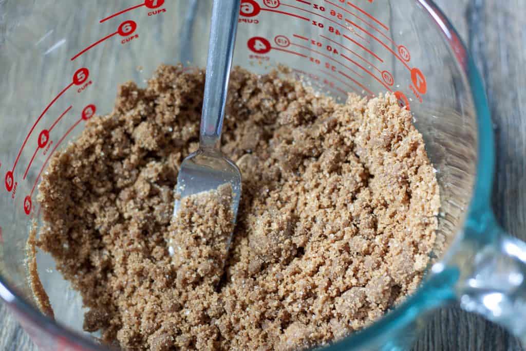 vegan gingersnap crust for the pumpkin pie bars in a large glass bowl with a fork.