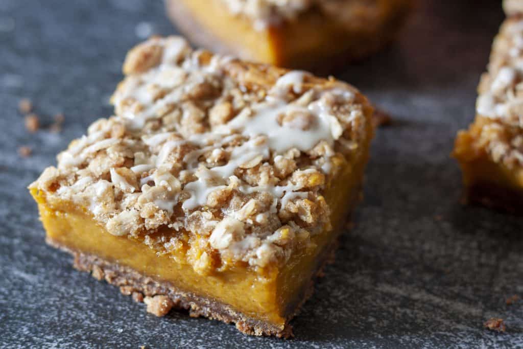 Single easy vegan pumpkin pie bar on a black background.
