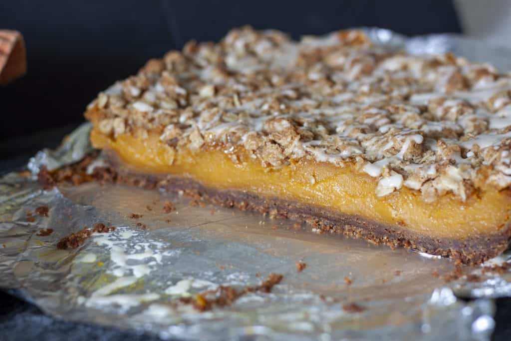 pumpkin pie bars cut in half on a foil background.