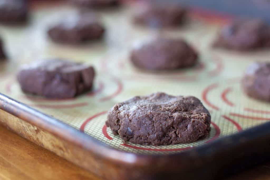 precooked vegan brownie cookies on a cookie sheet with a silpat. 