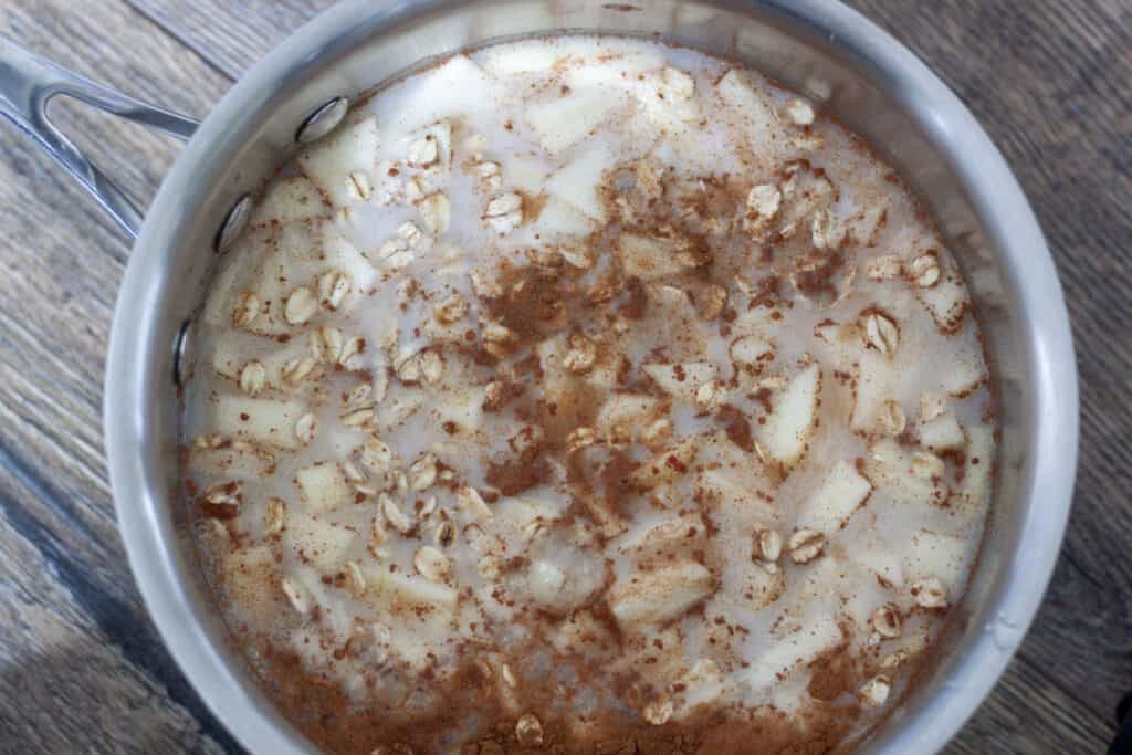 pre cooked vegan apple cinnamon oatmeal in a cooking pan on a wood background. 