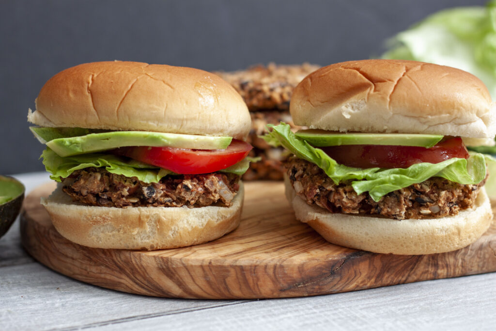 two vegan black bean burgers made up in buns on a wood background. 