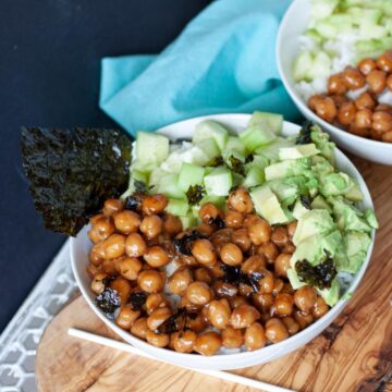 Vegan sushi bowl with chickpeas, cucumber and avocado on a wooden table.