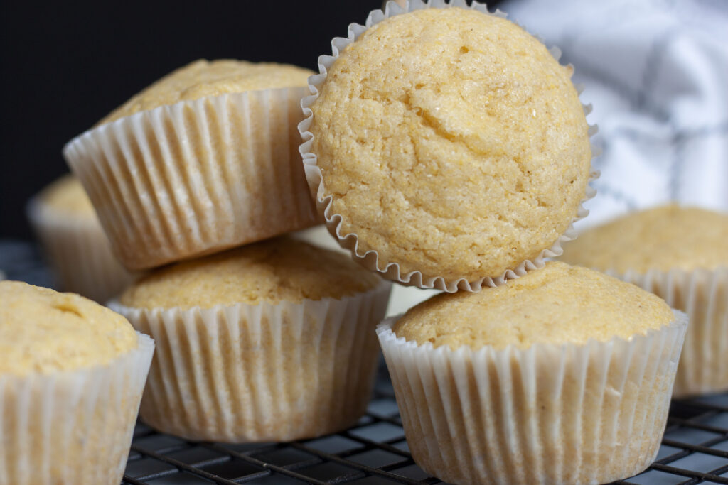 vegan corn muffins piled together on a cooling rack. 