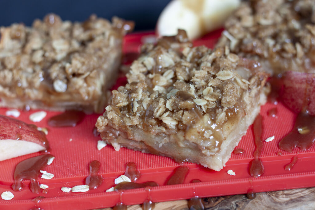 vegan caramel apple pie bars sliced on a red background. 