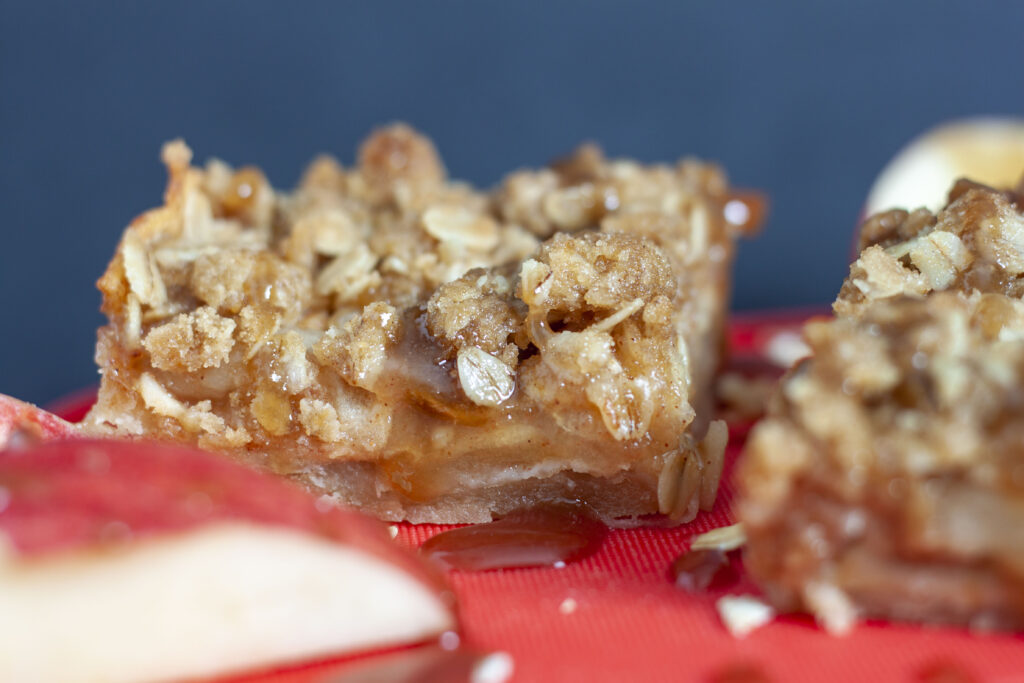 vegan apple pie crumb bars up close shot on a red background. 