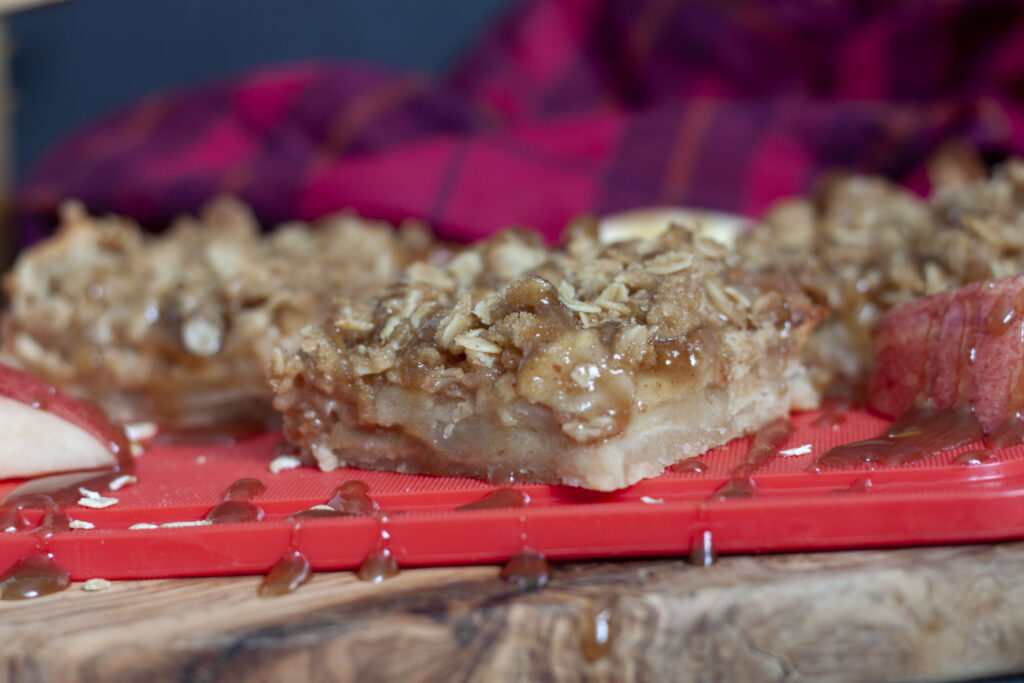 vegan caramel apple bars on a red plate with dripping caramel. 