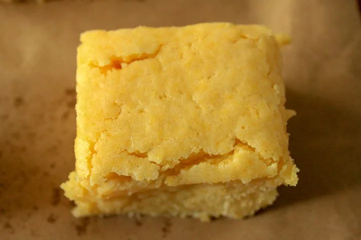 single piece of homemade vegan cornbread on a brown background.