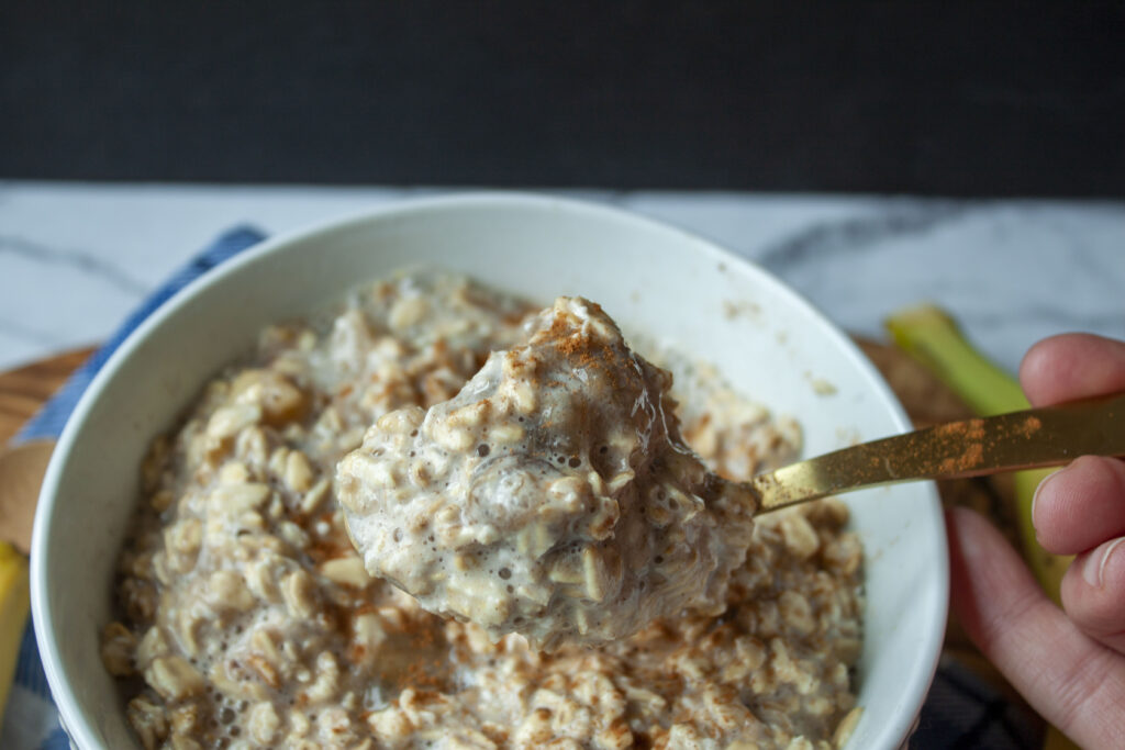 big bowl of vegan overnight oats with a spoon full on a gold spoon. 