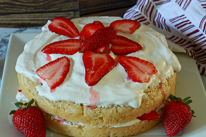 the best vegan strawberry shortcake cake on a plate decorated with whipping cream and strawberries. 
