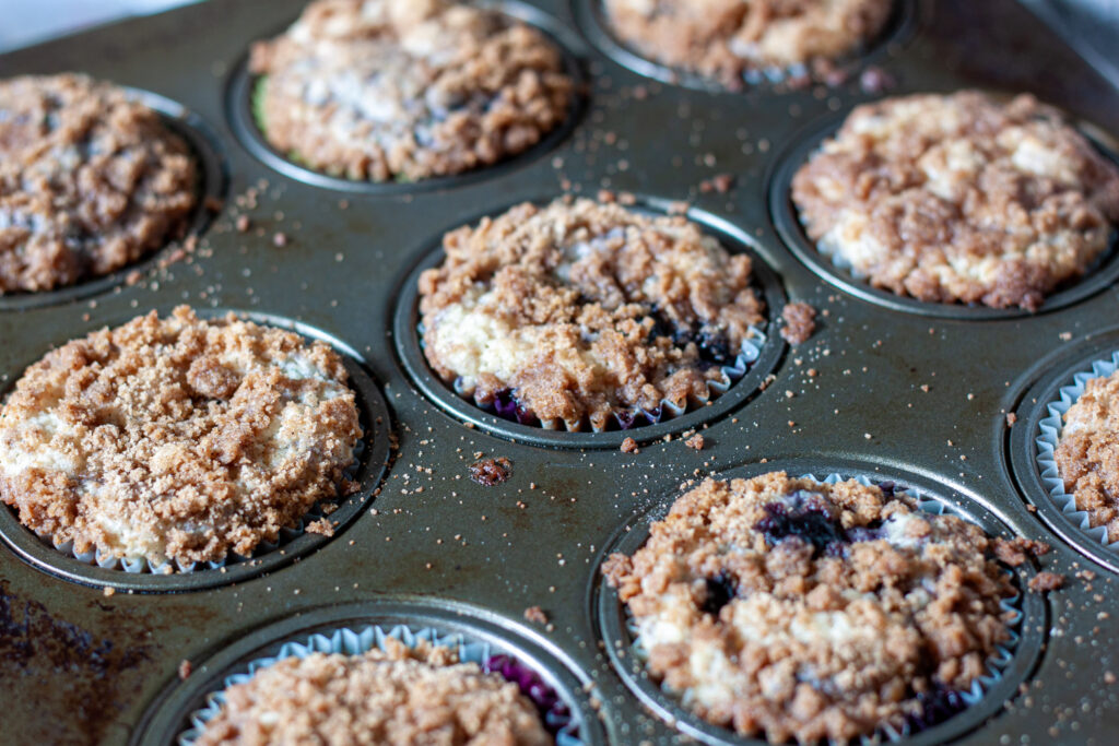 vegan muffin recipe cooked in a muffin tin with crumbs around it. 