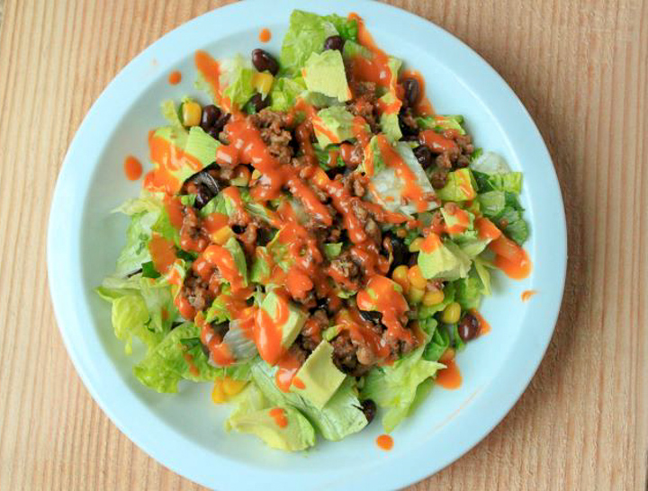 vegan taco salad on a white plate with a wood background. 