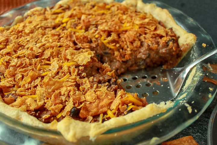 vegan taco pie in a dish with one slice out of it and spatula where the slice would be. 