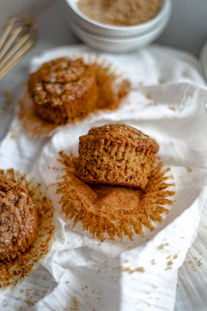 vegan pumpkin muffins on a white background with the muffin paper peeled back.