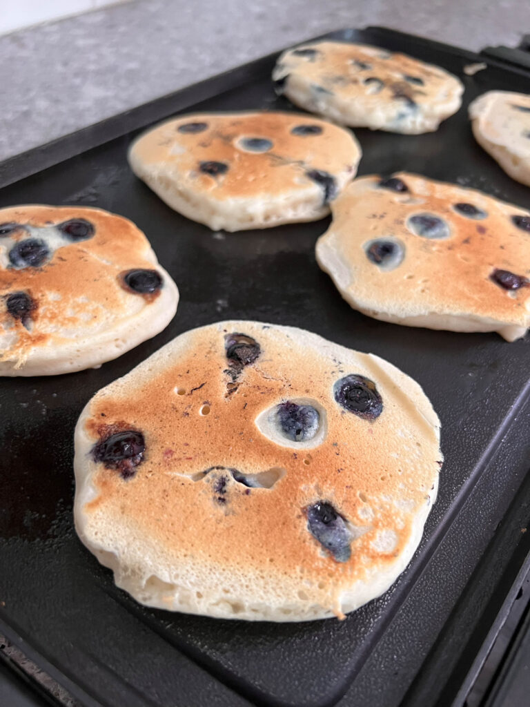 vegan blueberry pancakes cooking on the skillet