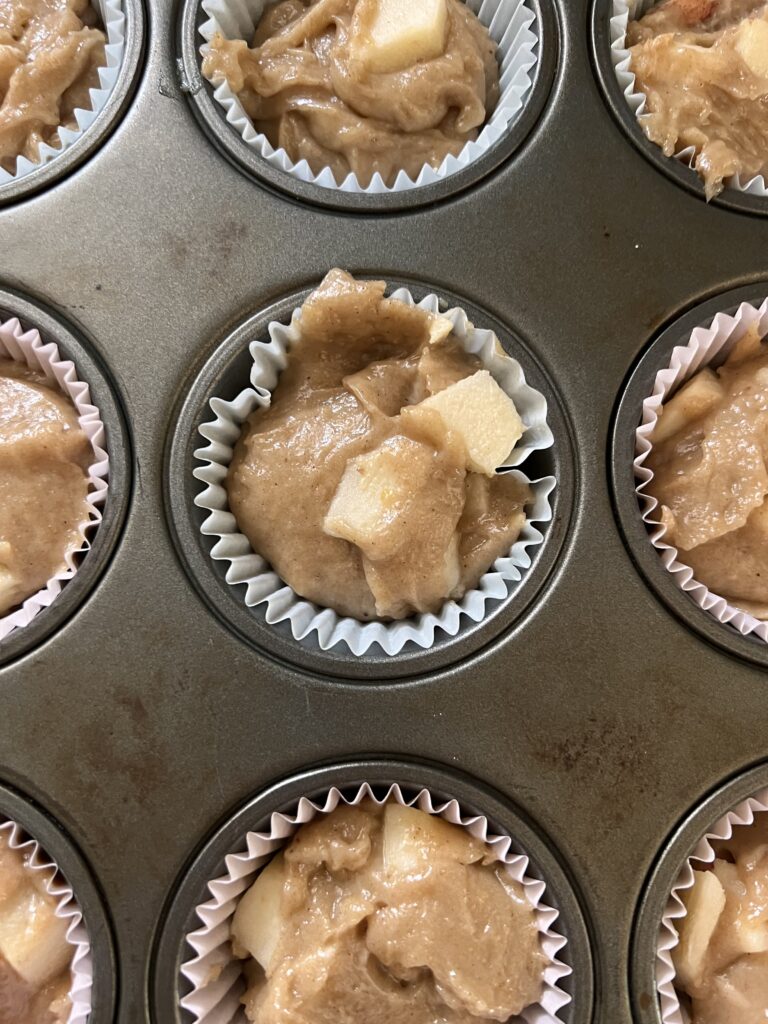vegan apple muffin batter in a muffin tin on the left and the right photo is the batter in the muffin tin with the streusal topping. 