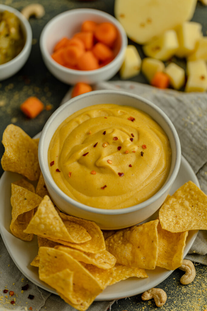 vegan nacho cheese sauce in a bowl on a plate with chips on the plate. 