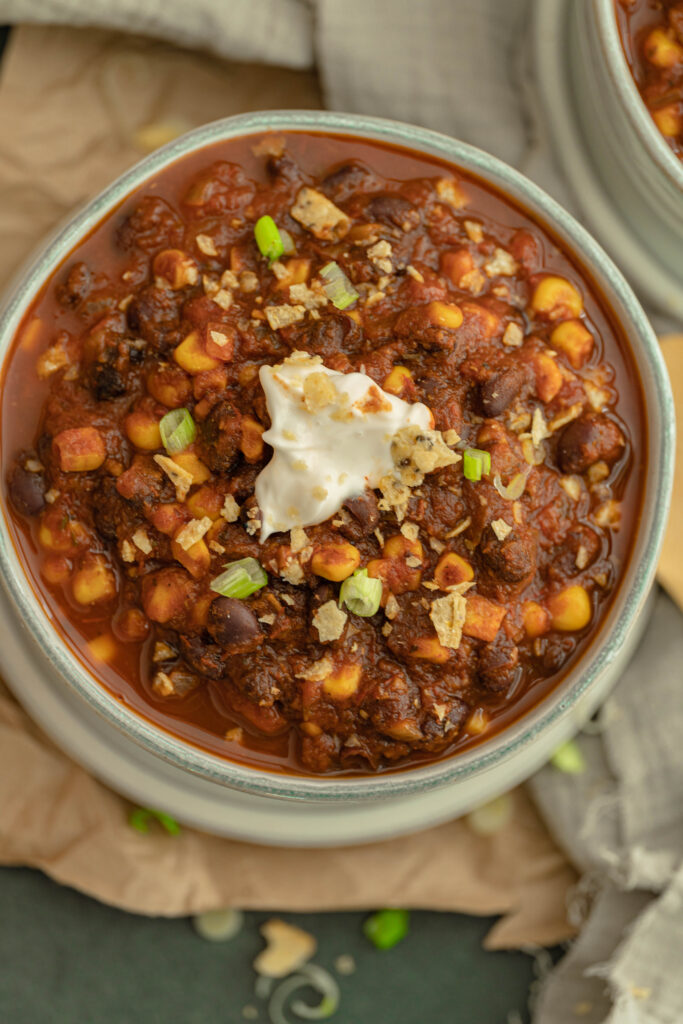 big bowl of vegan black bean chili in a bowl with sour cream toppings. 