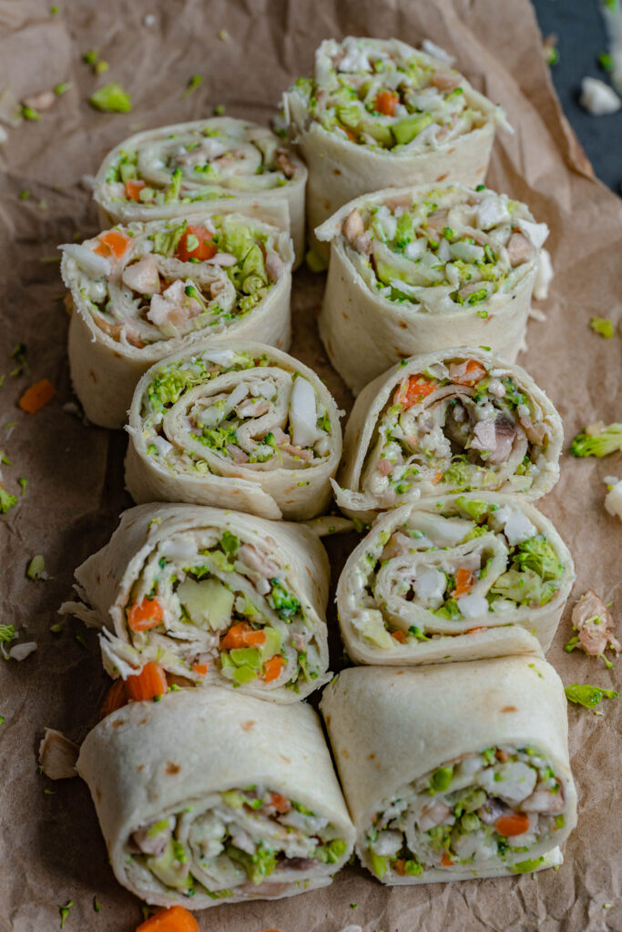 vegan vegetable ranch pinwheels all lined up on a brown paper bag background. 