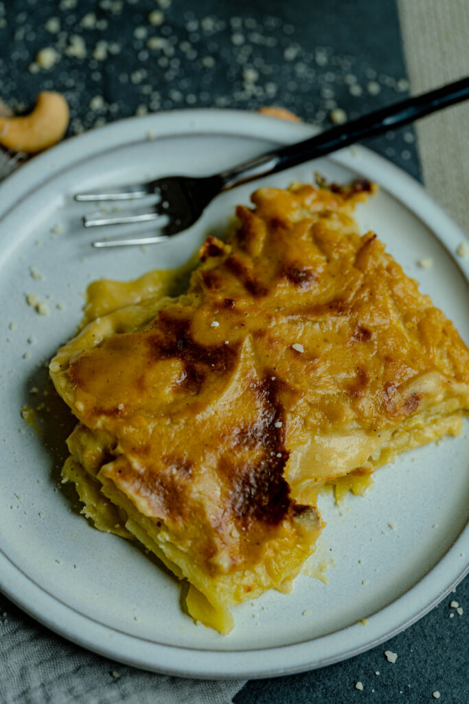 one square slice vegan scalloped potatoes on a white plate with crumbs. 