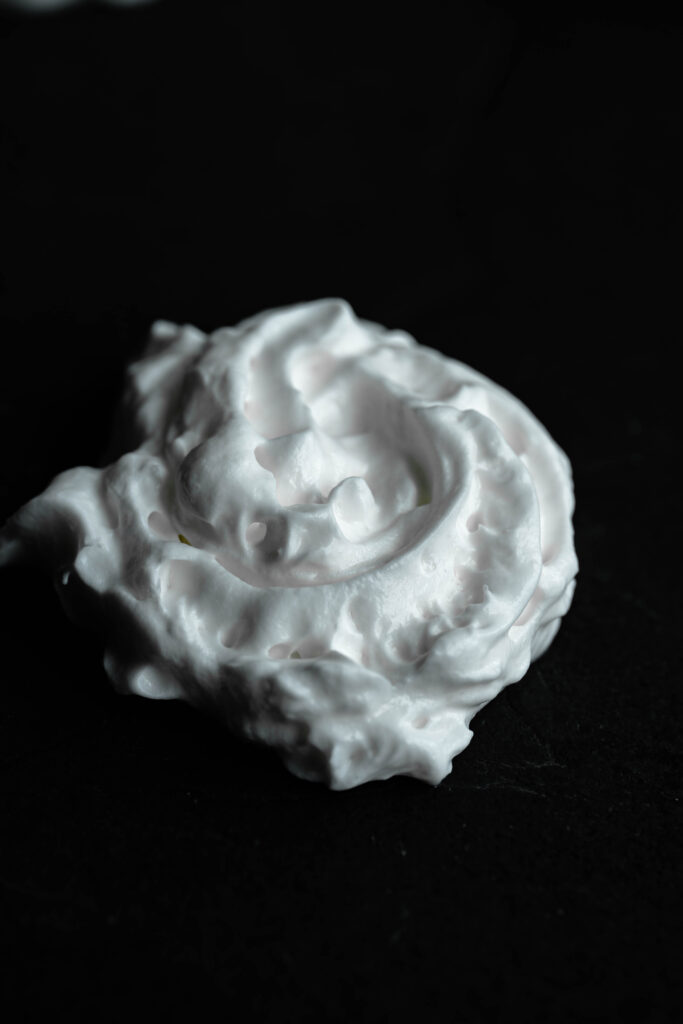 vegan whipped topping dollop on a black background.