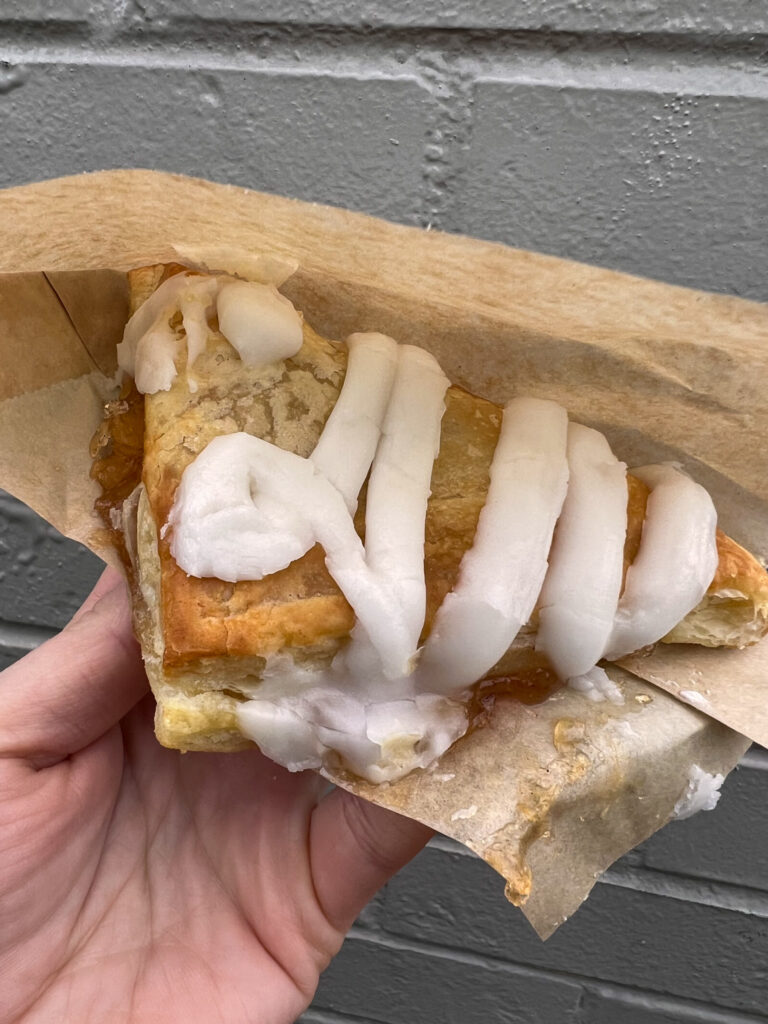 vegan apple turnover from arbys in a hand against a brick wall. 