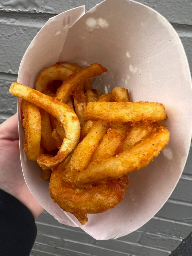 vegan arby curly fries in it's container being held by a hand. 