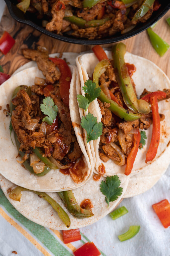 vegan fajitas made up in corn tortillas on a white and colorful towel. 