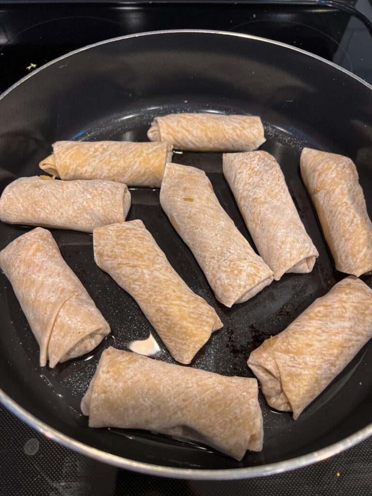 frying vegan egg rolls in a deep skillet with a shallow amount of oil. 