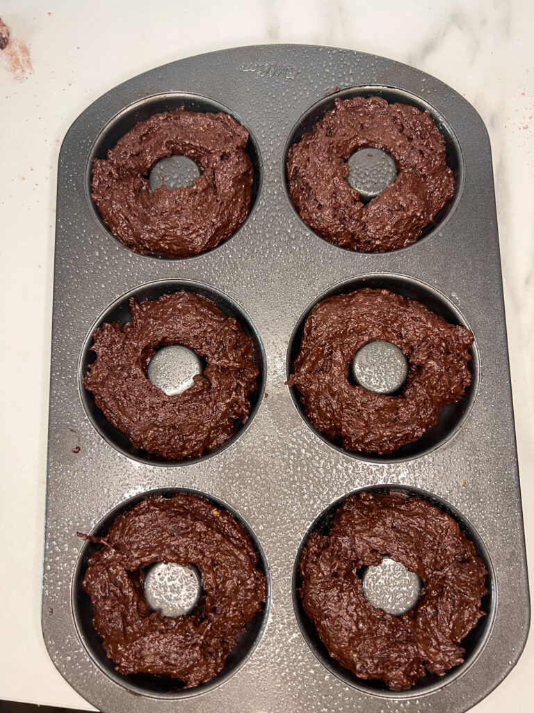 uncooked chocolate vegan donut batter in a donut pan.