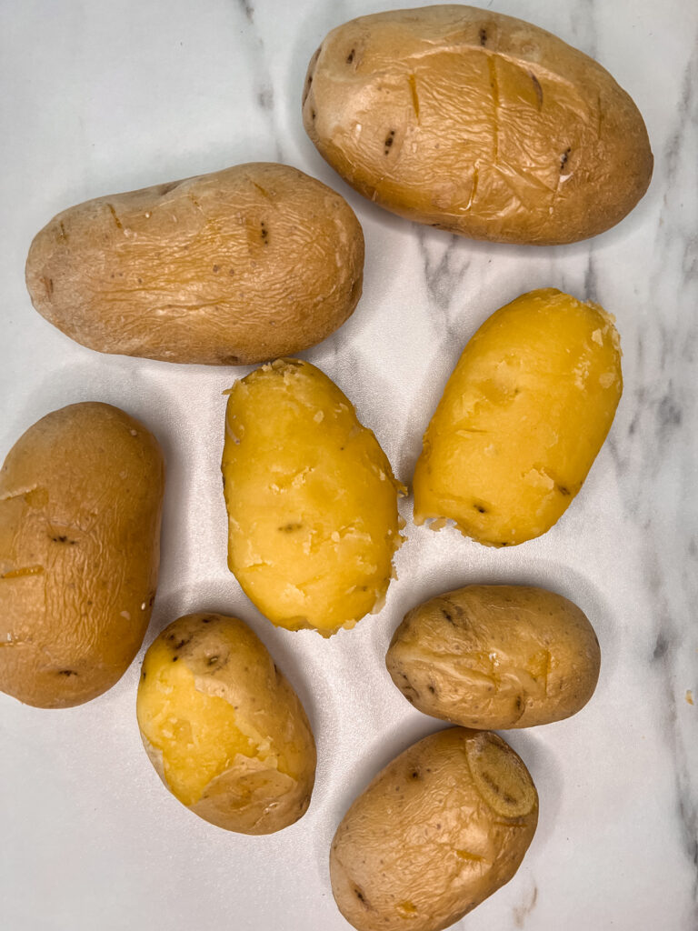 half peeled, not peeled potatoes on a marble background. 